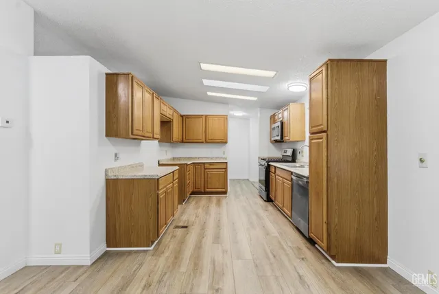 a kitchen with granite countertop a refrigerator oven a sink dishwasher and wooden cabinets