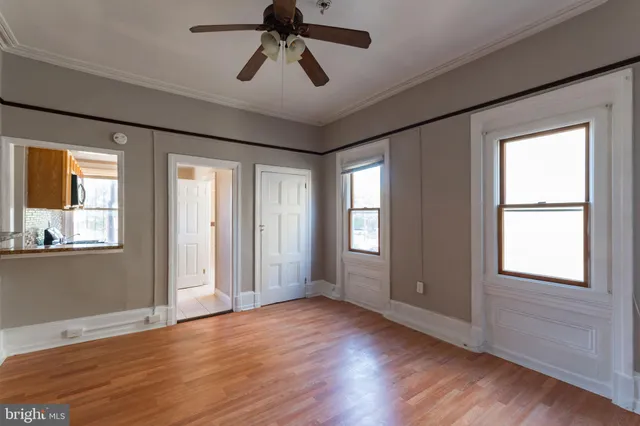a view of empty room with wooden floor and fan