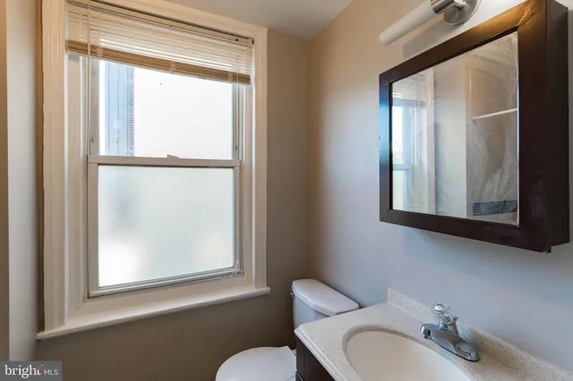 a bathroom with a sink mirror and a window