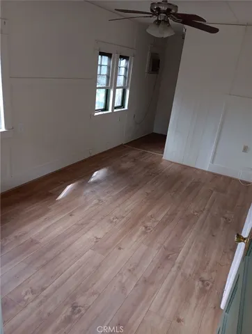 an empty room with wooden floor fan and windows
