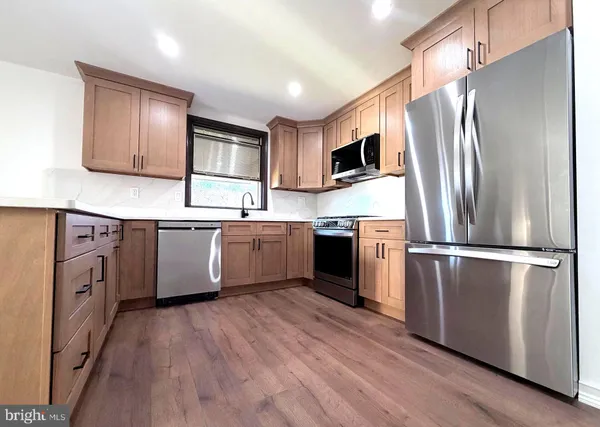 a kitchen with stainless steel appliances granite countertop a refrigerator a stove a sink dishwasher and white cabinets with wooden floor