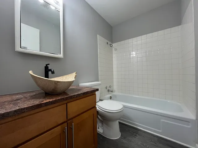 a bathroom with a granite countertop toilet sink and mirror