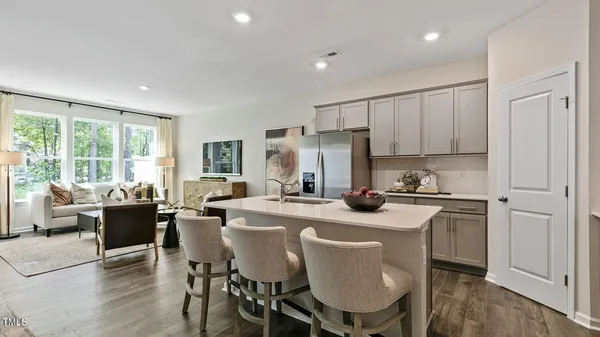 a kitchen with stainless steel appliances granite countertop a dining table chairs refrigerator and cabinets