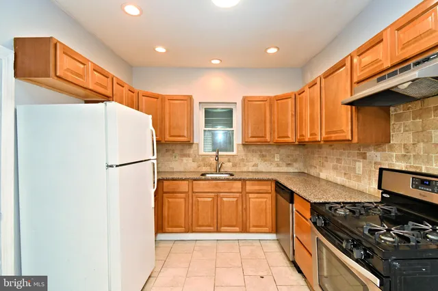 a kitchen with a sink a refrigerator and a stove top oven with wooden floor