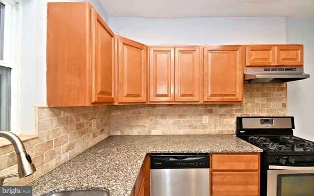 a kitchen with stainless steel appliances granite countertop a stove a sink and a microwave