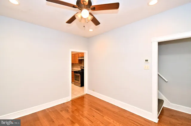 an empty room with wooden floor chandelier fan and entryway