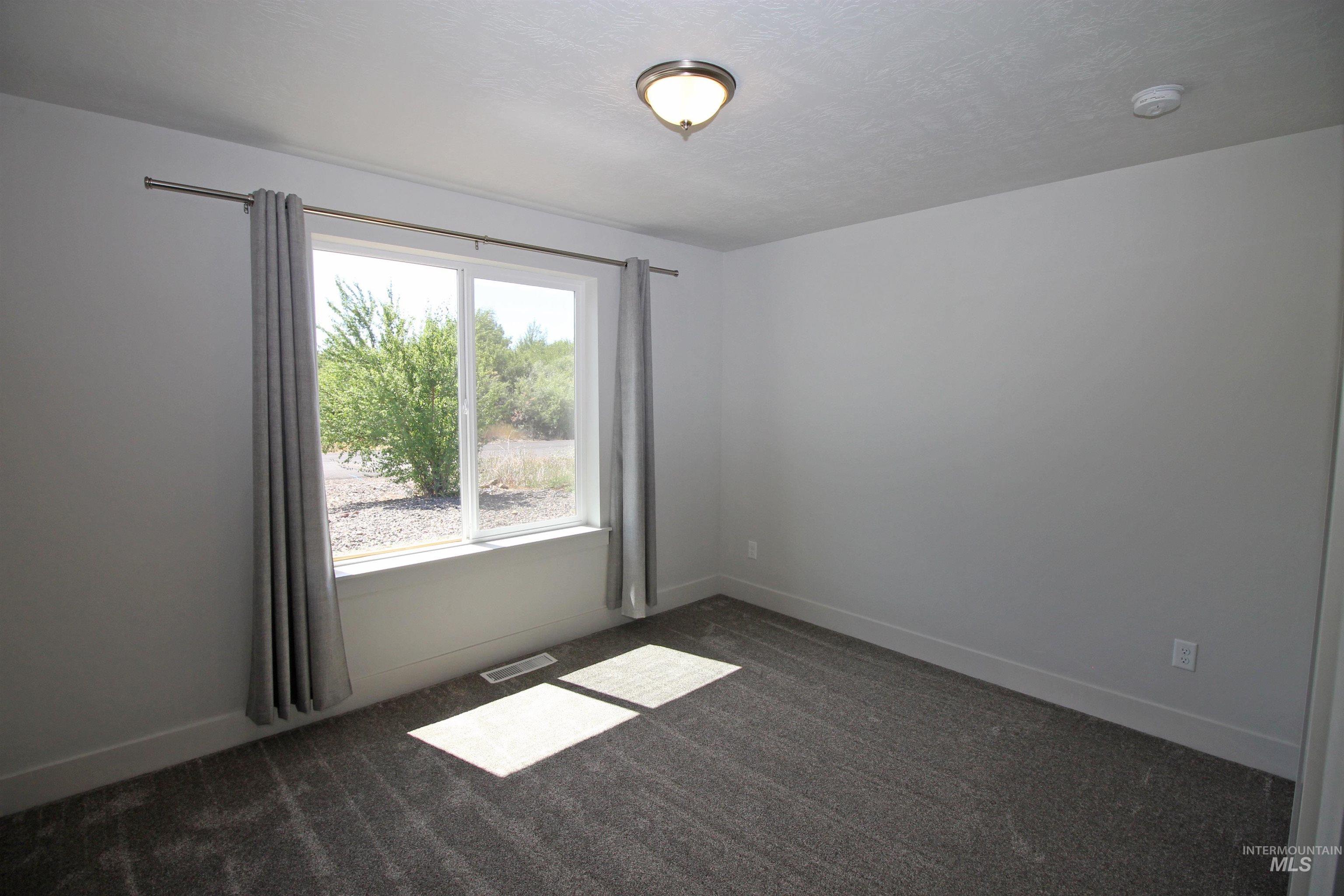 2272 Golf Lane Council, ID 83612 - Photo 18 of 32 Unfurnished room featuring dark colored carpet and a textured ceiling