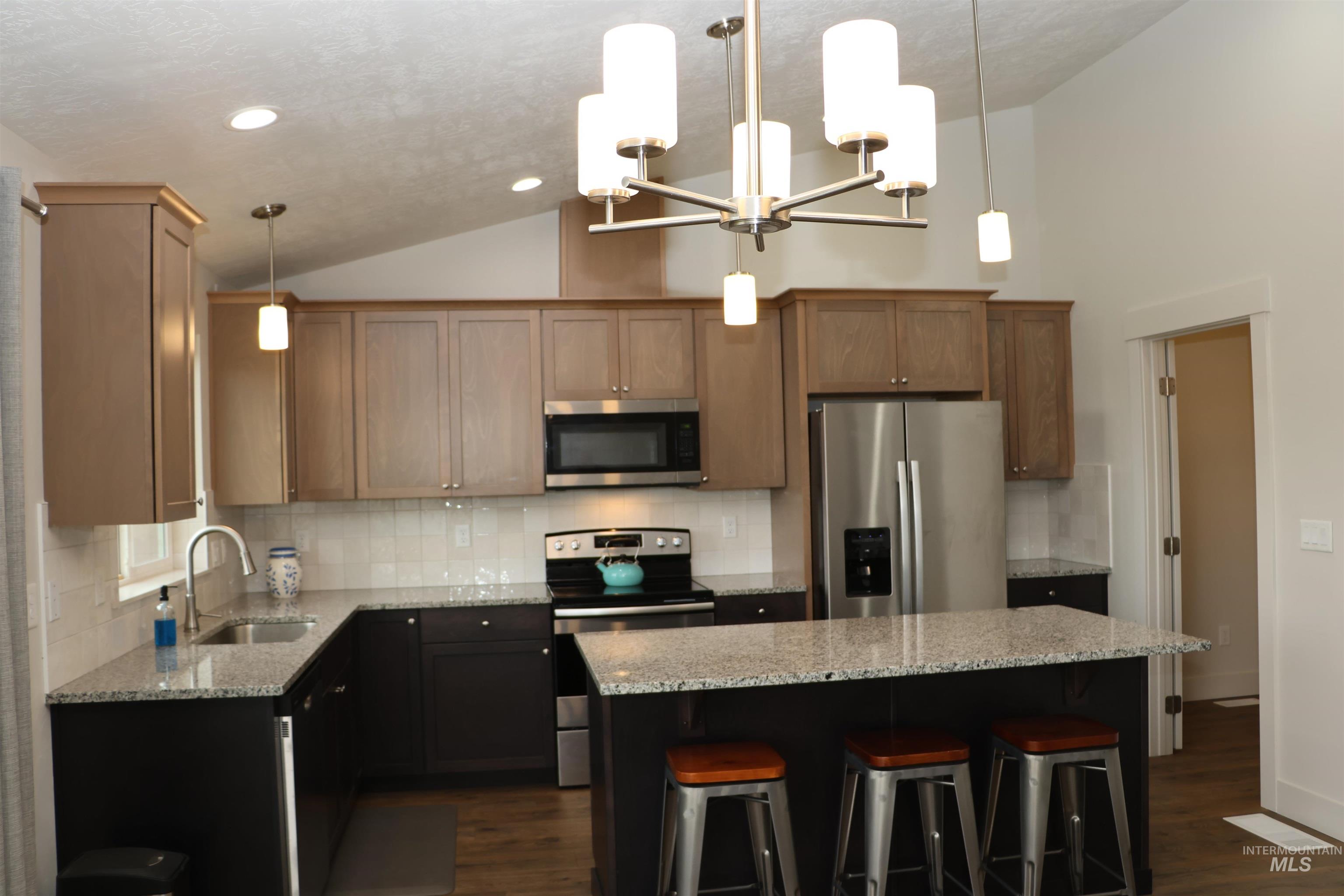 2272 Golf Lane Council, ID 83612 - Photo 6 of 32 Kitchen featuring stainless steel appliances, dark wood-style flooring, a kitchen island, light stone counters, and decorative backsplash