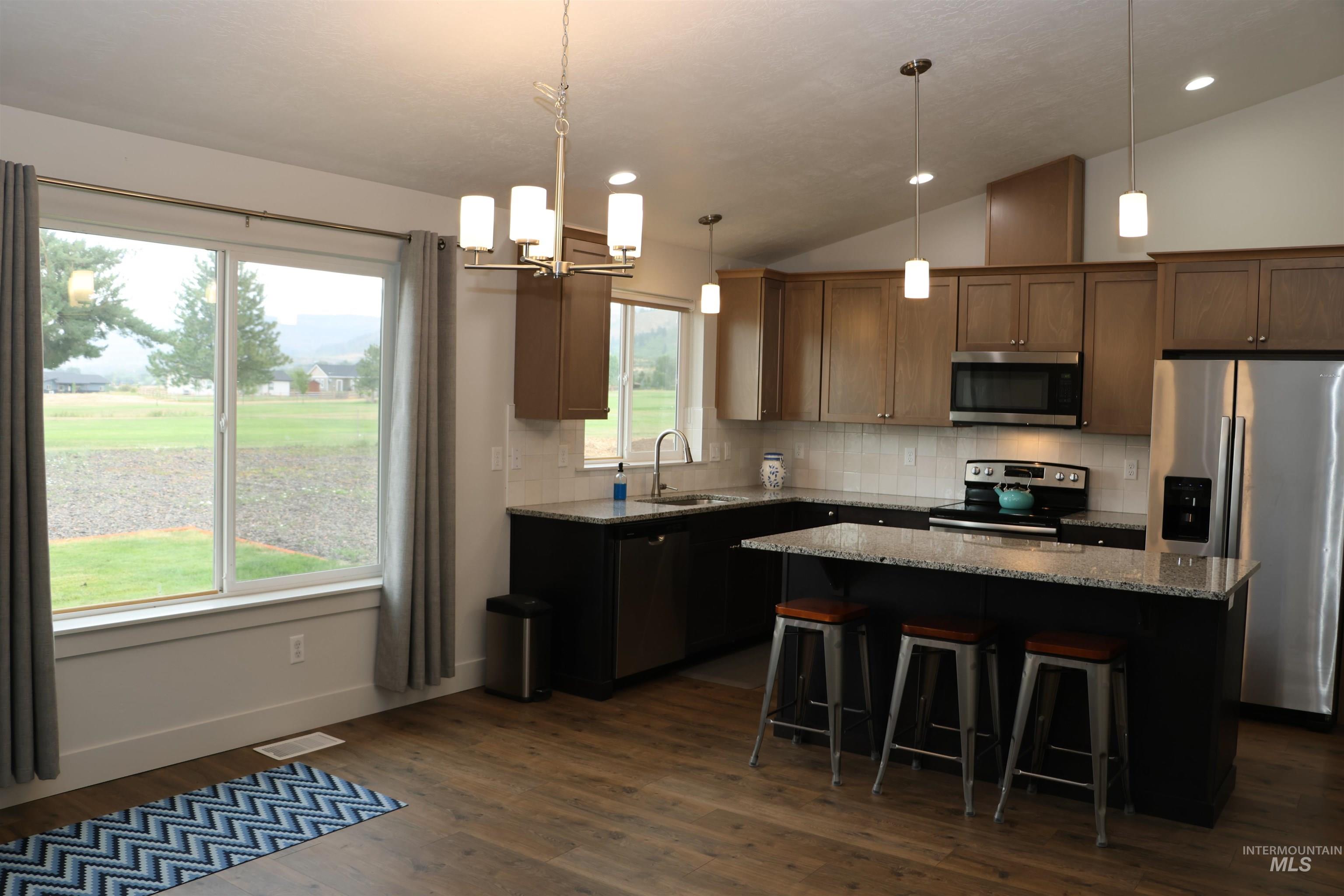2272 Golf Lane Council, ID 83612 - Photo 7 of 32 Kitchen featuring lofted ceiling, stainless steel appliances, a kitchen island, dark wood-type flooring, and light stone countertops