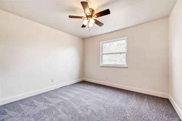 an empty room with windows and fan