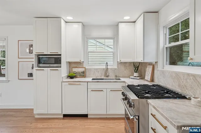 a kitchen with stainless steel appliances granite countertop a stove a sink dishwasher a refrigerator and a microwave oven with wooden floor