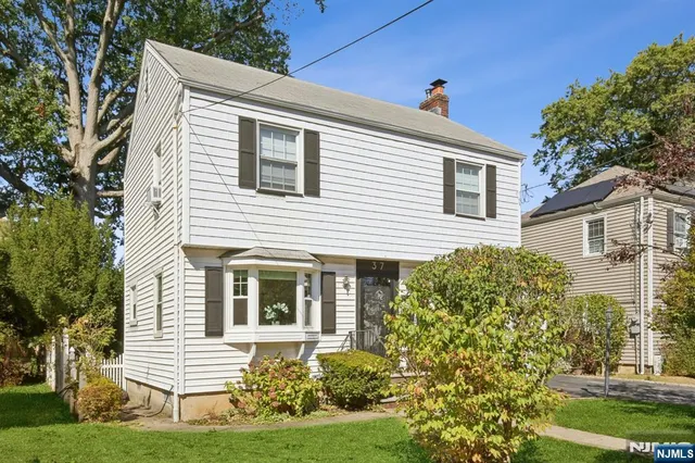 a view of a white house with a small yard and potted plants