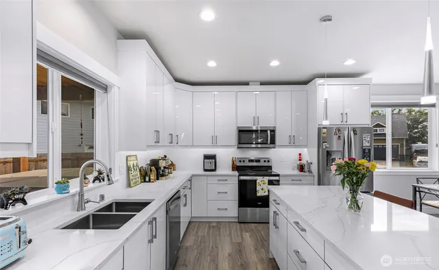 a kitchen with granite countertop a sink a counter top space stainless steel appliances and cabinets