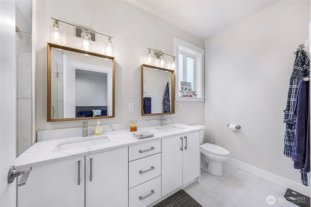 a bathroom with a double vanity sink a toilet and a mirror