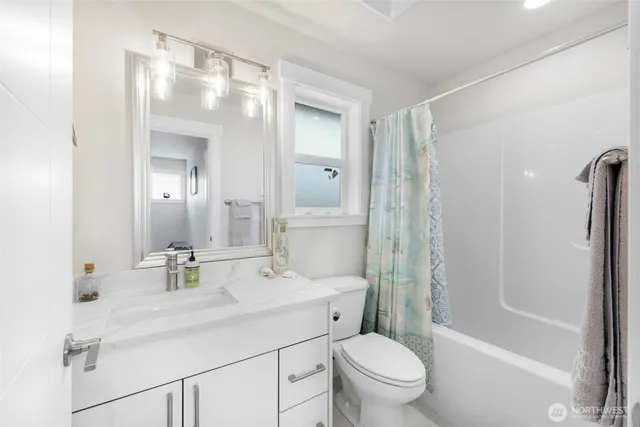 a bathroom with a sink a toilet a mirror a vanity and shower