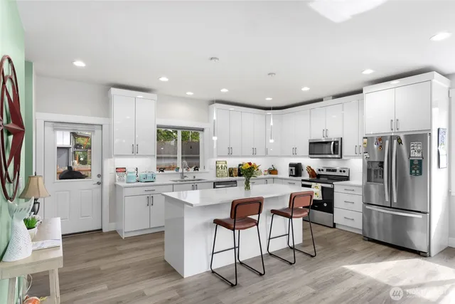 a kitchen with stainless steel appliances a refrigerator a stove a sink a dining table and chairs