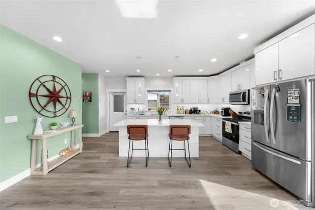 a kitchen with stainless steel appliances granite countertop a refrigerator oven a sink dishwasher and white cabinets with wooden floor