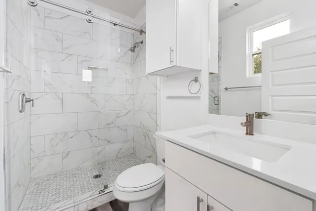 a bathroom with a sink a toilet and shower