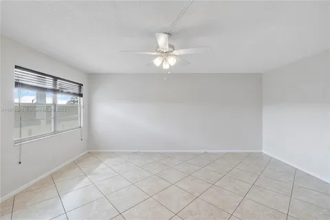 an empty room with a ceiling fan and glass door