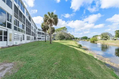 a view of a lake with a big yard and large trees
