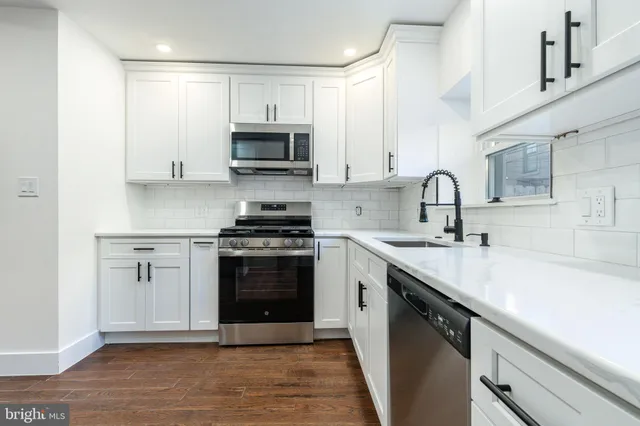 a kitchen with stainless steel appliances granite countertop a sink dishwasher a stove and a microwave oven with cabinets