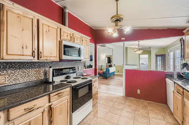 a kitchen with granite countertop a stove a microwave oven a sink and dishwasher with granite countertops