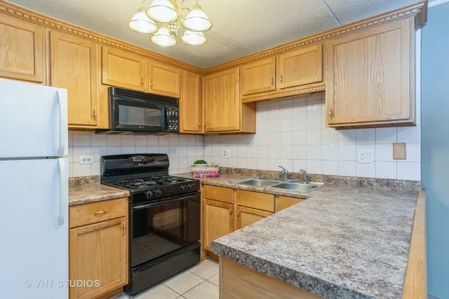 a kitchen with granite countertop a stove top oven a sink dishwasher and white cabinets with wooden floor