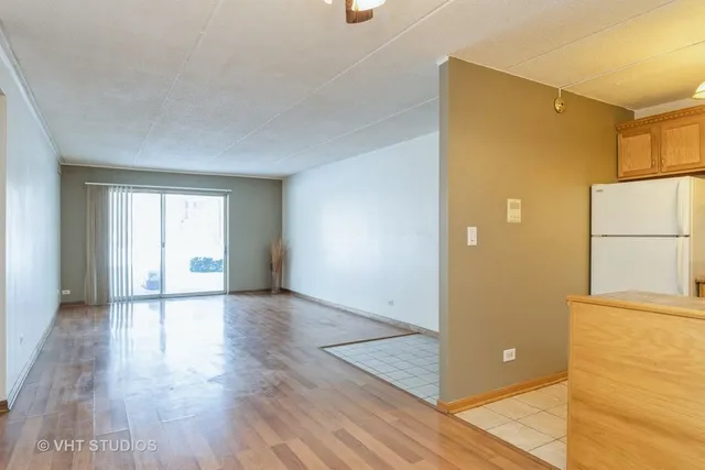 a view of a livingroom with wooden floor and a refrigerator