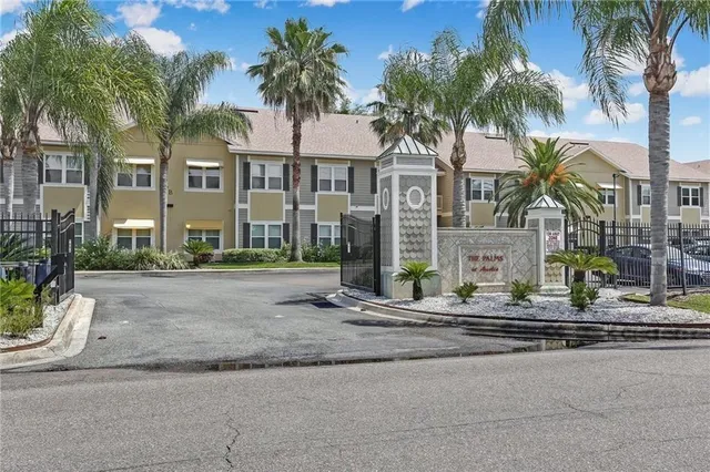 a view of a house with a yard and palm trees