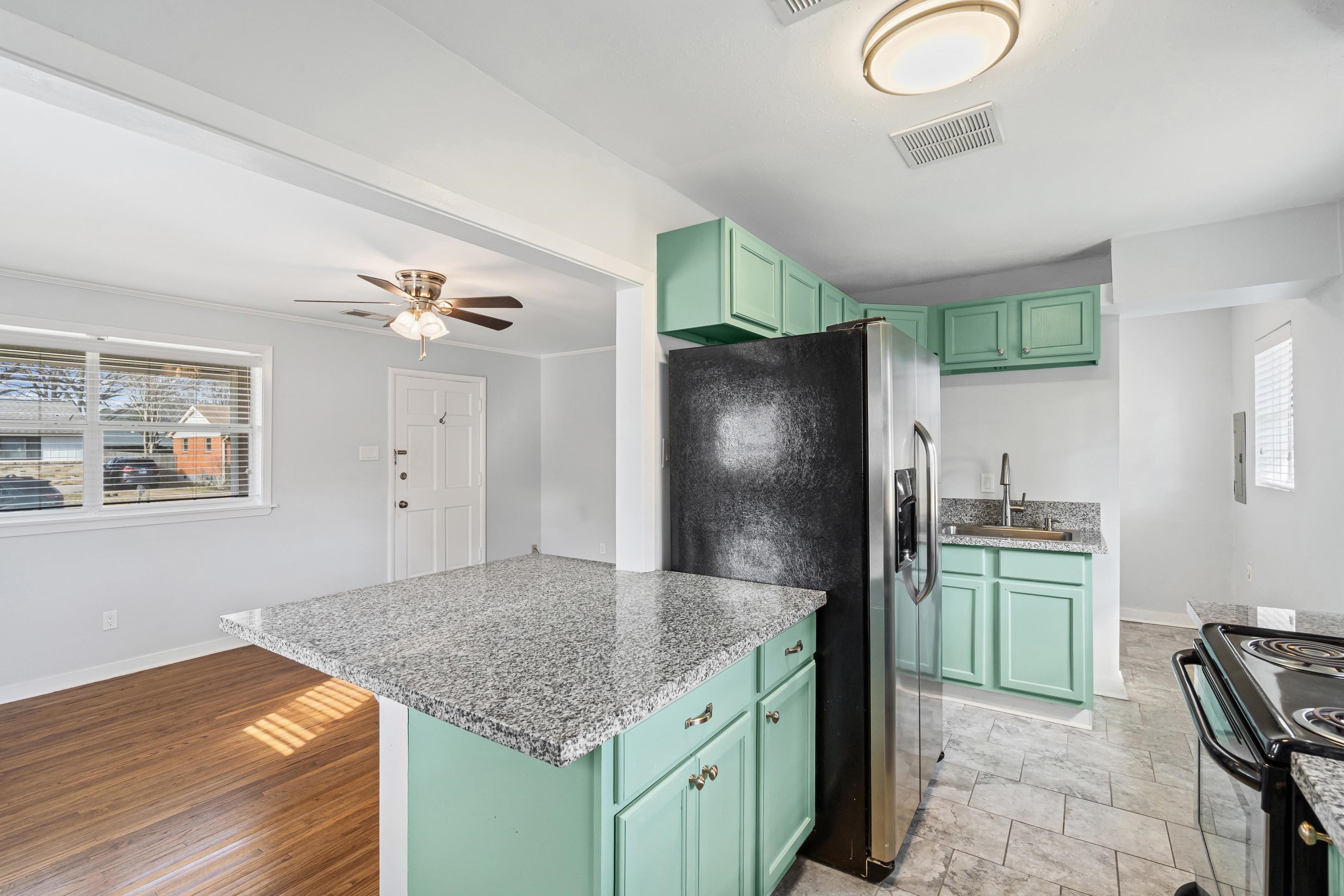 506 McDermitt Road Memphis, TN 38120 - Photo 11 of 29 Kitchen with green cabinetry, light stone countertops, stainless steel fridge with ice dispenser, and ceiling fan