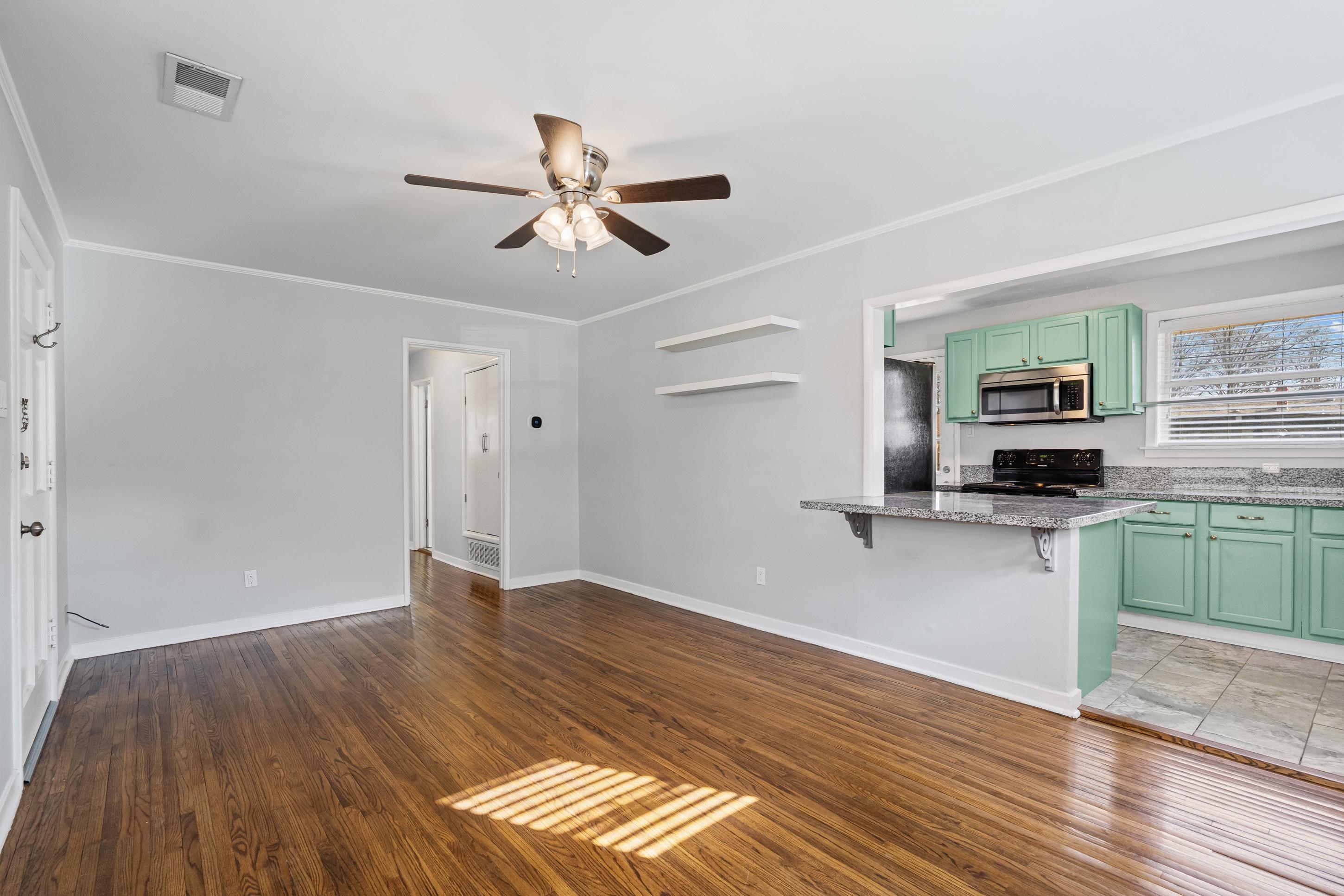 506 McDermitt Road Memphis, TN 38120 - Photo 5 of 29 Unfurnished living room with dark wood-style flooring, crown molding, and a ceiling fan