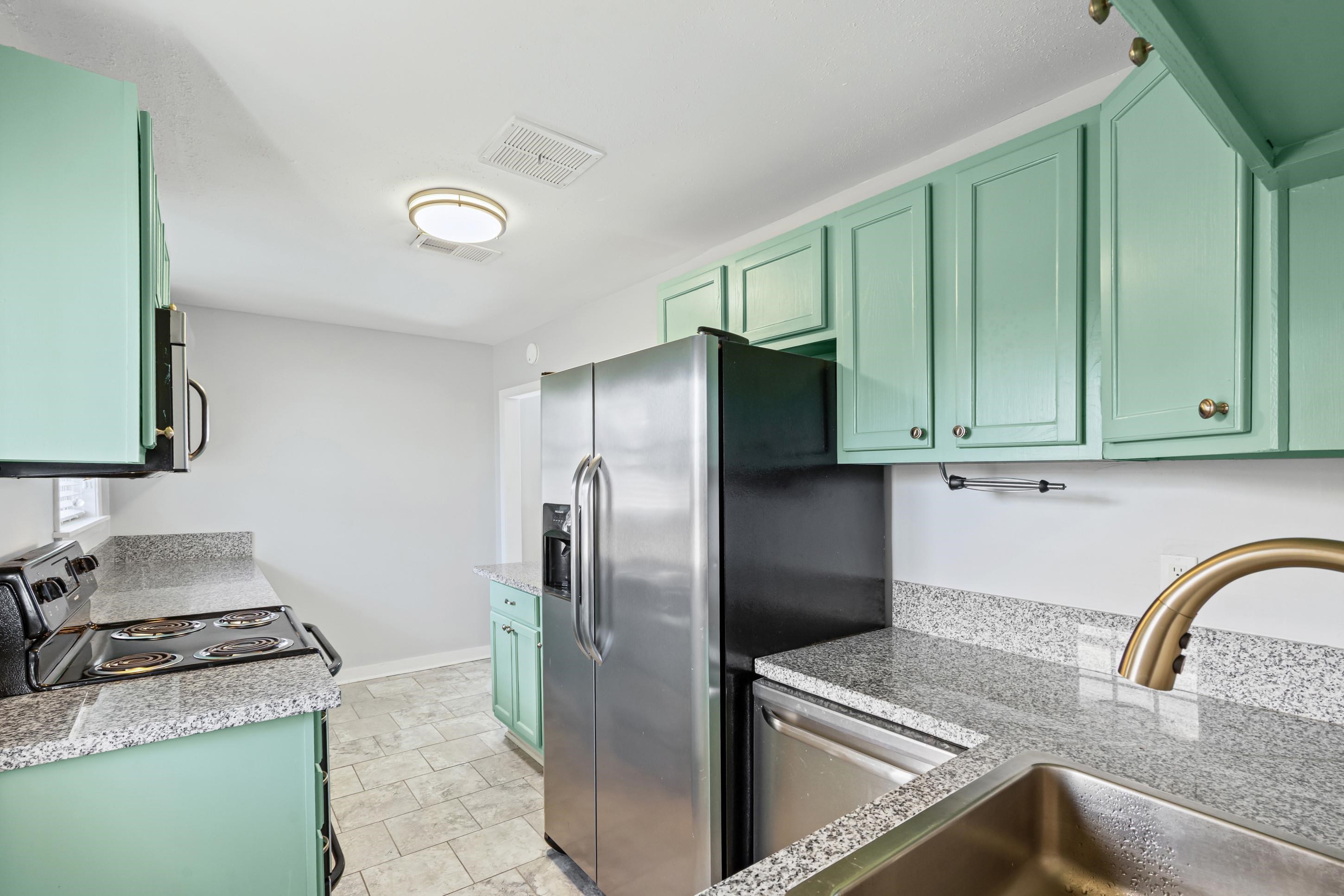 506 McDermitt Road Memphis, TN 38120 - Photo 8 of 29 Kitchen with green cabinets, light stone counters, and stainless steel appliances
