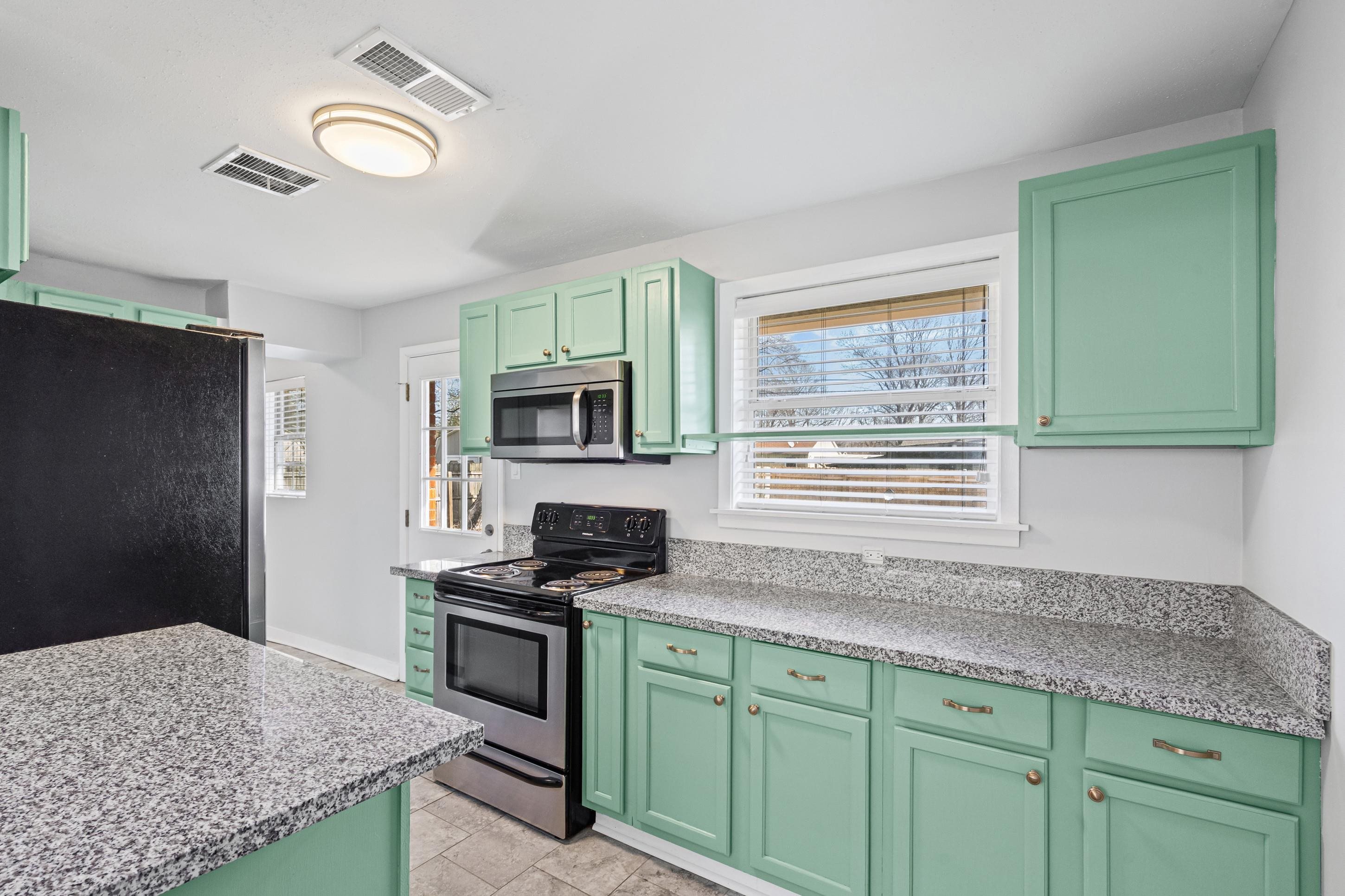 506 McDermitt Road Memphis, TN 38120 - Photo 10 of 29 Kitchen featuring green cabinets, stainless steel appliances, and light stone countertops