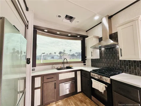 a kitchen with stainless steel appliances granite countertop a refrigerator a stove and a sink