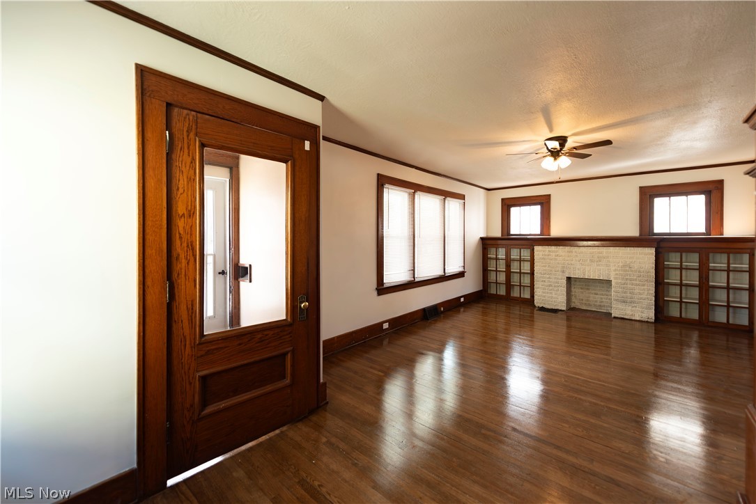 1022 North Howard Street Akron, OH 44310 - Photo 2 of 38 Living room featuring a brick fireplace, ceiling fan, a Spanish knockdown ceiling, and gorgeously refinished dark hardwood flooring