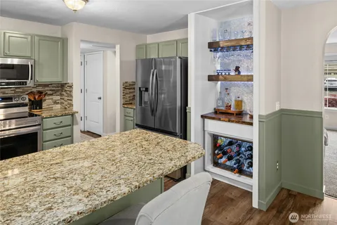 a kitchen with stainless steel appliances kitchen island granite countertop a refrigerator and a stove top oven