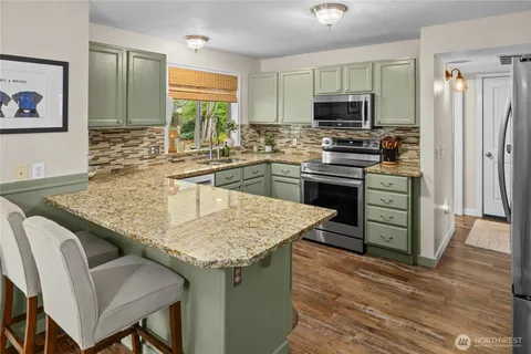 a kitchen with stainless steel appliances granite countertop a kitchen island hardwood floor sink and stove