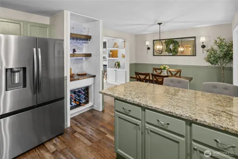 a kitchen with stainless steel appliances granite countertop a refrigerator a stove and a sink with wooden floors