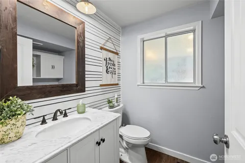 a bathroom with a granite countertop sink mirror vanity and toilet