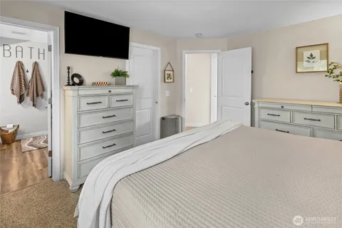 a bedroom with a bed and a flat tv screen on the dresser