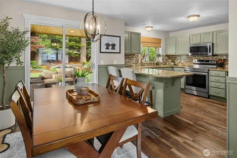 a kitchen with stainless steel appliances granite countertop a stove a table and chairs in it