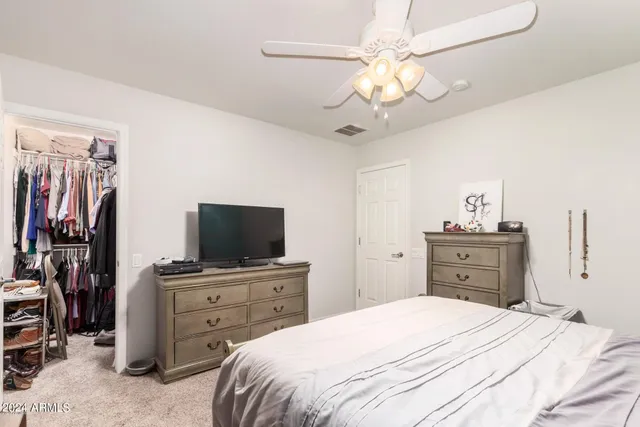a bedroom with a bed and a flat tv screen on dresser