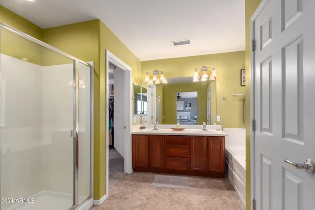 a bathroom with a double vanity sink and mirror with shower