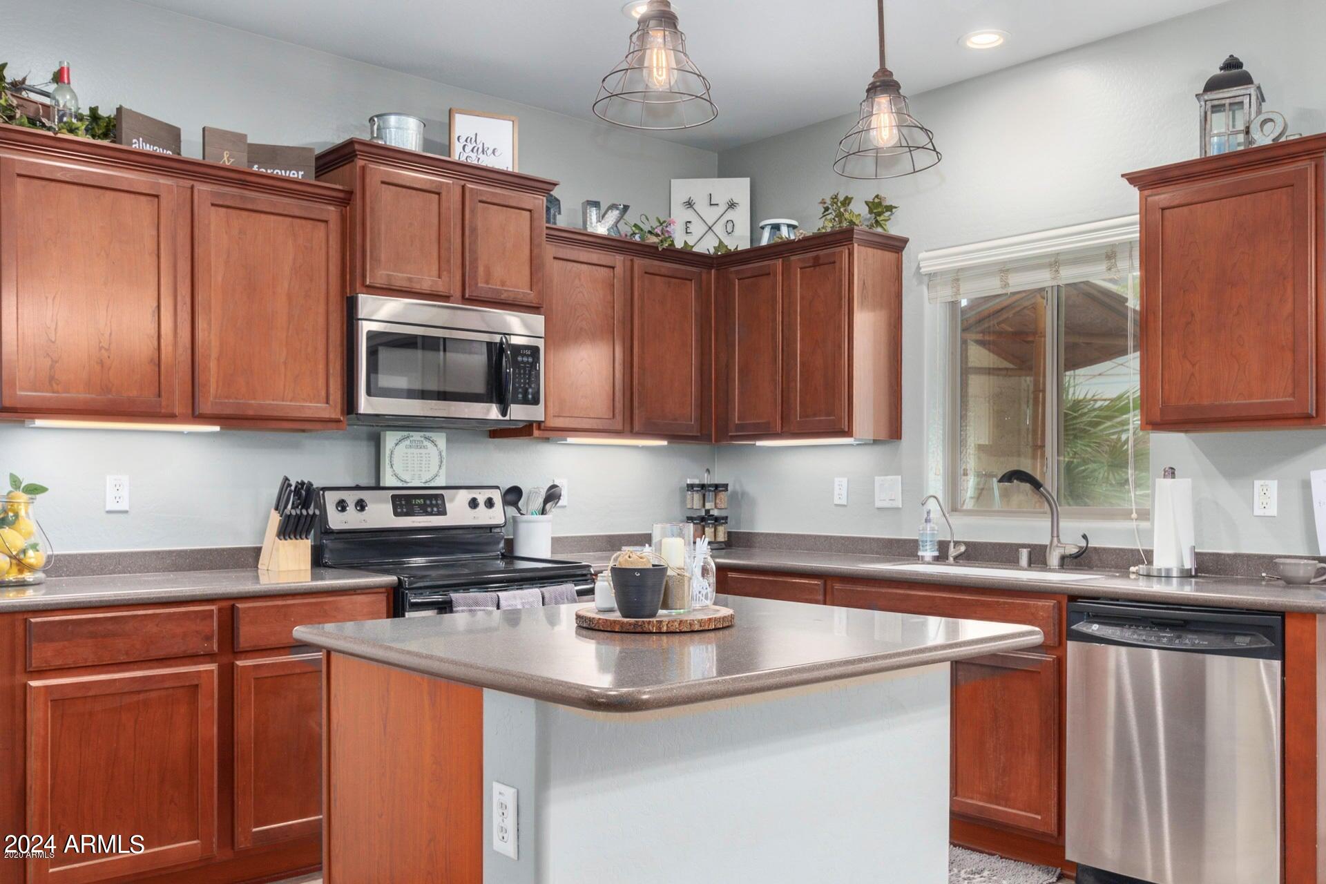 2217 West Kathleen Road Phoenix, AZ 85023 - Photo 10 of 42 a kitchen with stainless steel appliances granite countertop a sink dishwasher a stove top oven a refrigerator with wooden cabinets and a window