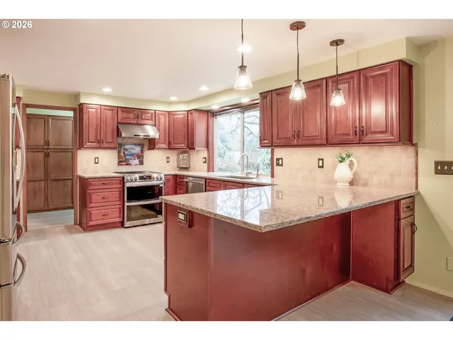 a kitchen with stainless steel appliances granite countertop a sink a stove and a refrigerator