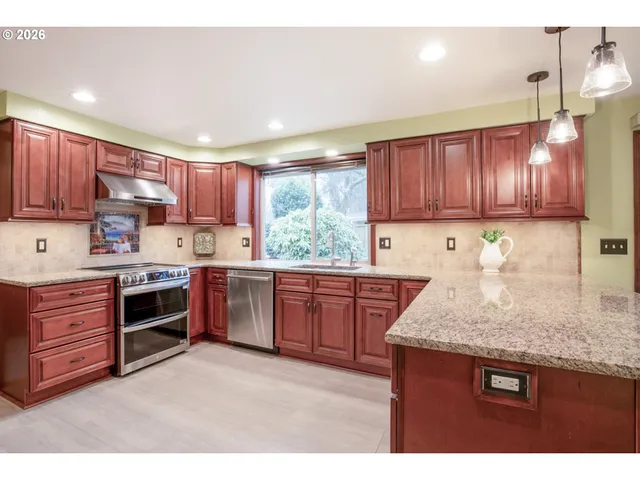 a kitchen with kitchen island granite countertop wooden cabinets a stove a sink and dishwasher