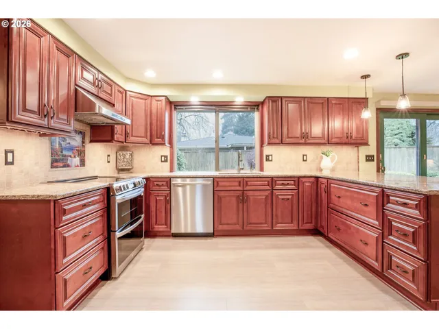 a kitchen with stainless steel appliances granite countertop a stove a sink dishwasher and a refrigerator