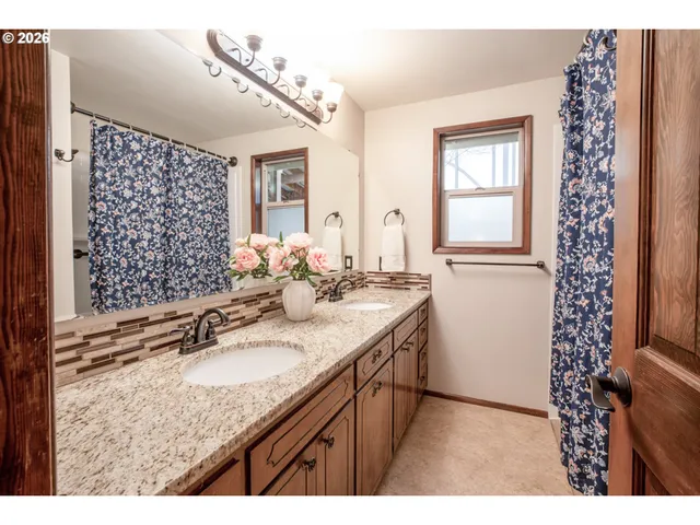 a bathroom with a granite countertop sink a mirror a vanity and a shower