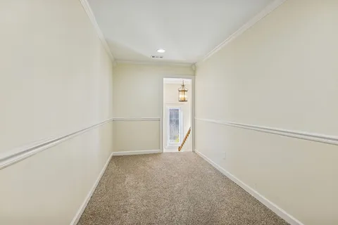 an empty room with wooden floor chandelier and windows