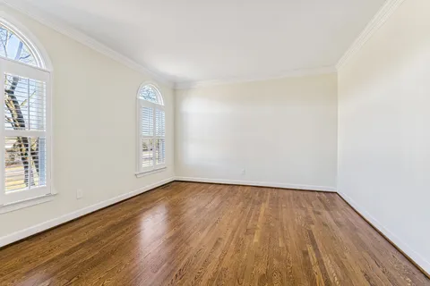 a view of an empty room with wooden floor and window